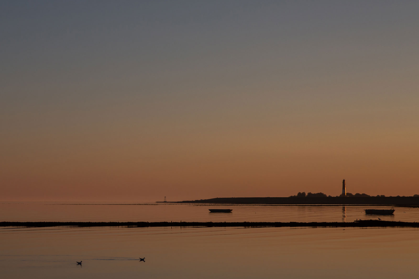 Pellworm ankommen - unendliche Weite, glatte Nordsee, Sonnenuntergang und in weiter Ferne der Leuchtturm 