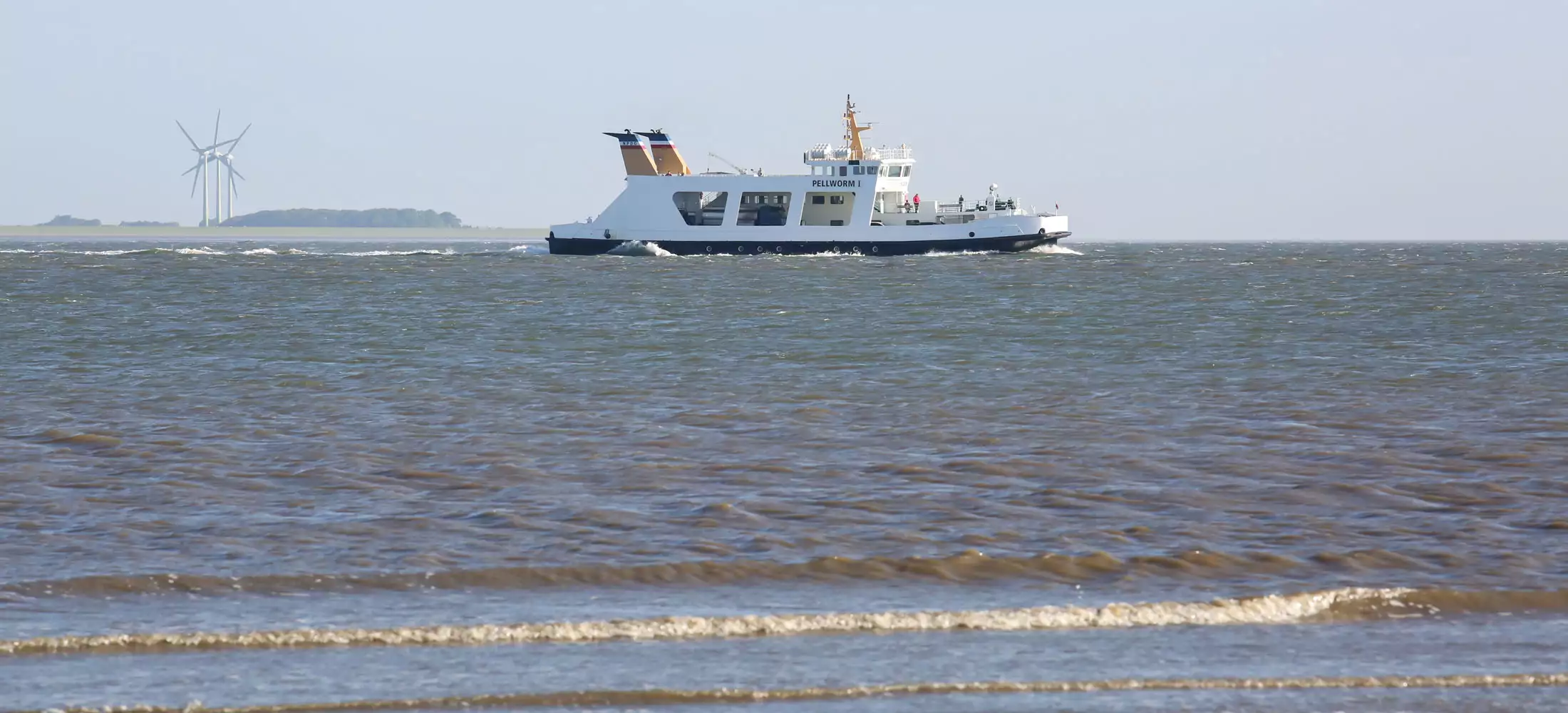 Wattlandschaft bei Flut auf Pellworm mit vorbeifahrender Fähre