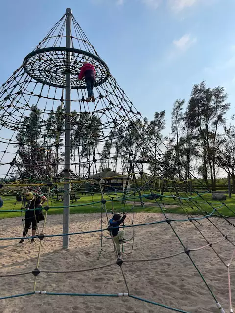 Kinder klettern am Kletternetz auf dem Abenteuerspielplatz auf Pellworm und haben Spaß