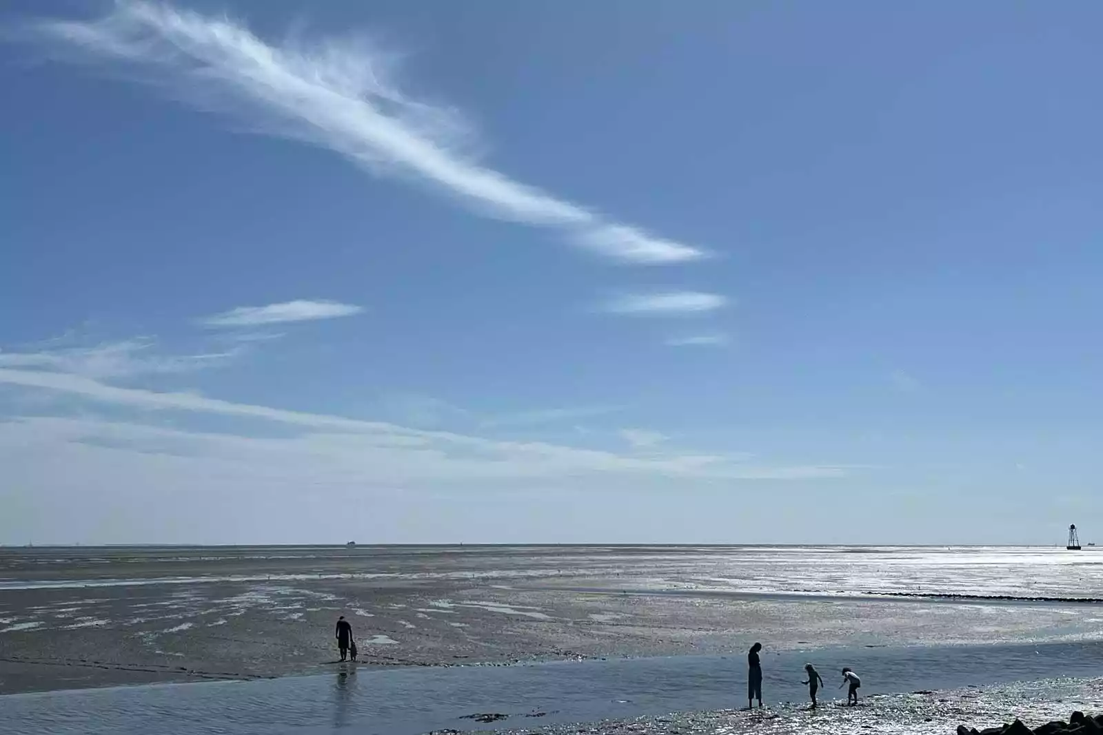 Weite im Watt – unterwegs bei Ebbe unter sommerlichem Himmel.