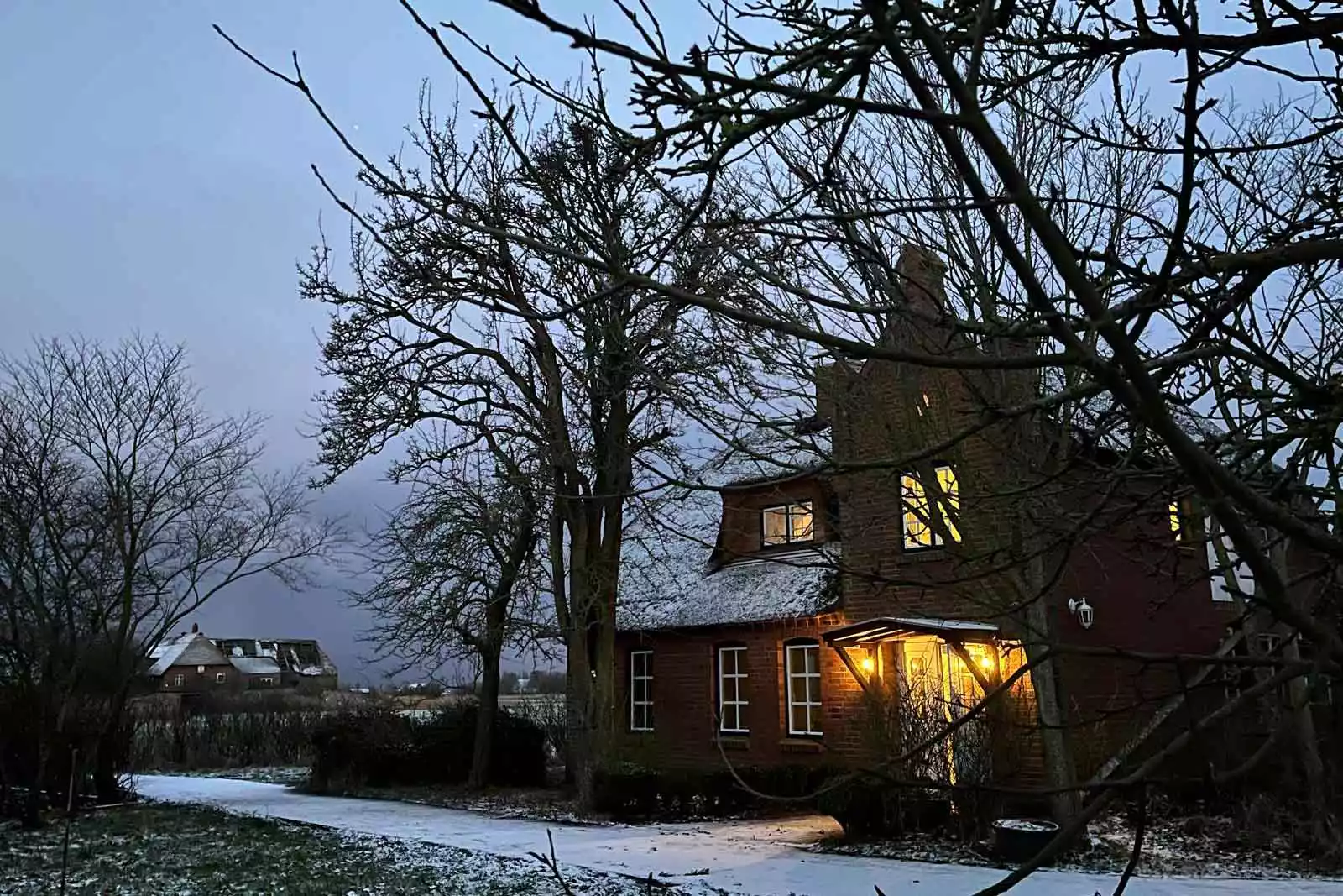 Beleuchtetes Ferienhaus Deichschlösschen auf Pellworm in winterlicher Dämmerung – warme Ankunft nach Spaziergang