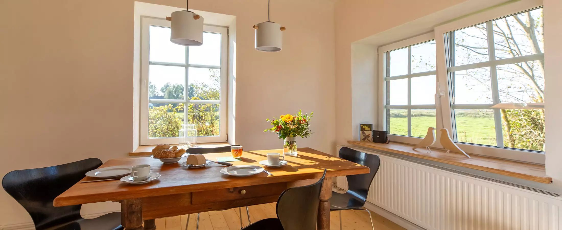 Lichtdurchflutetes Esszimmer im Deichschlösschen mit eingedecktem Frühstückstisch für 2 Personen