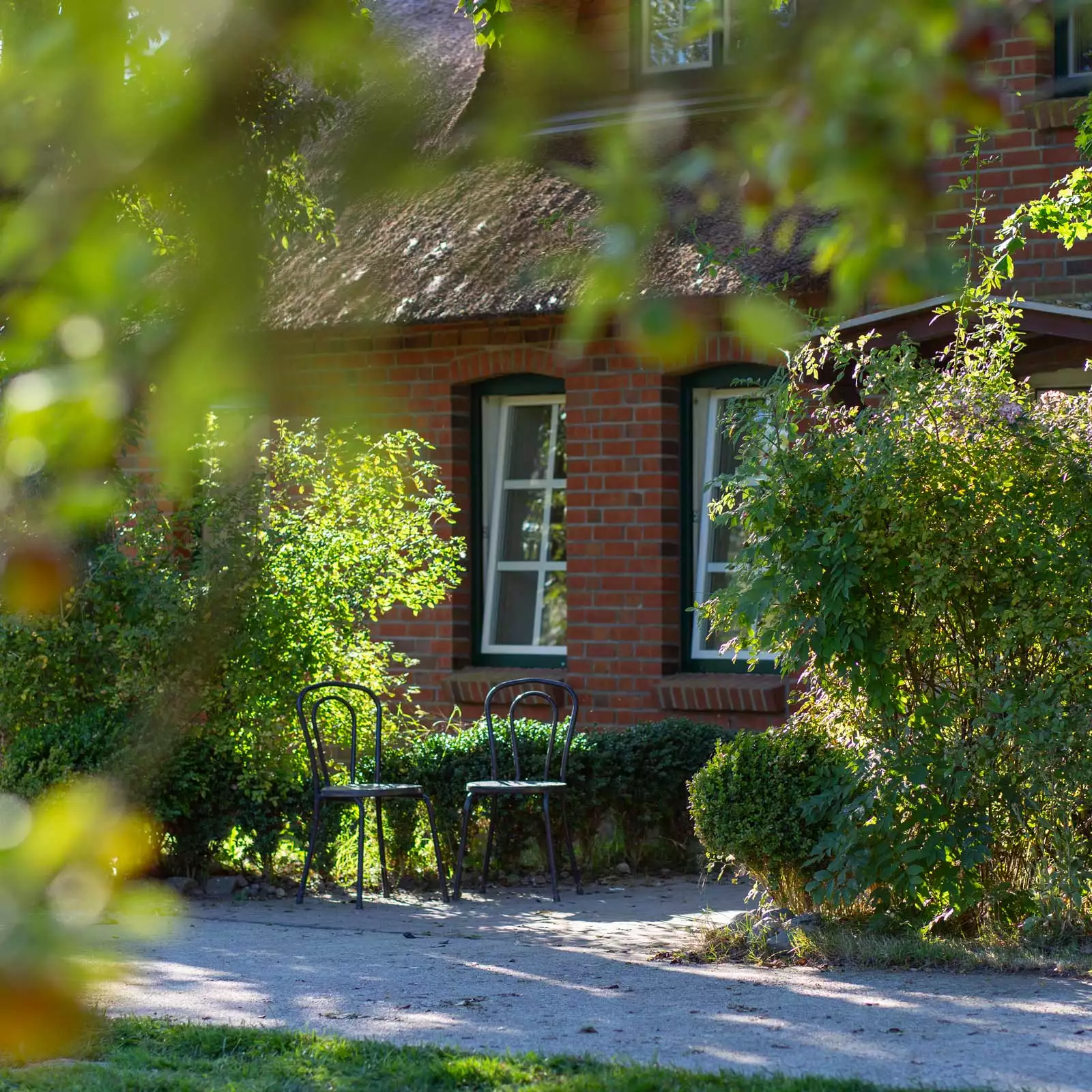 Ferienhaus Deichschlösschen auf Pellworm mit Reetdach und zwei Stühlen am Eingang