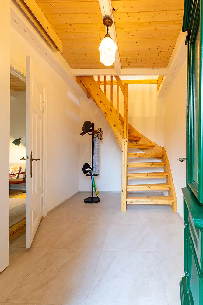 Heller Flur im Ferienhaus Deichschlösschen mit Holztreppe ins Dachgeschoss