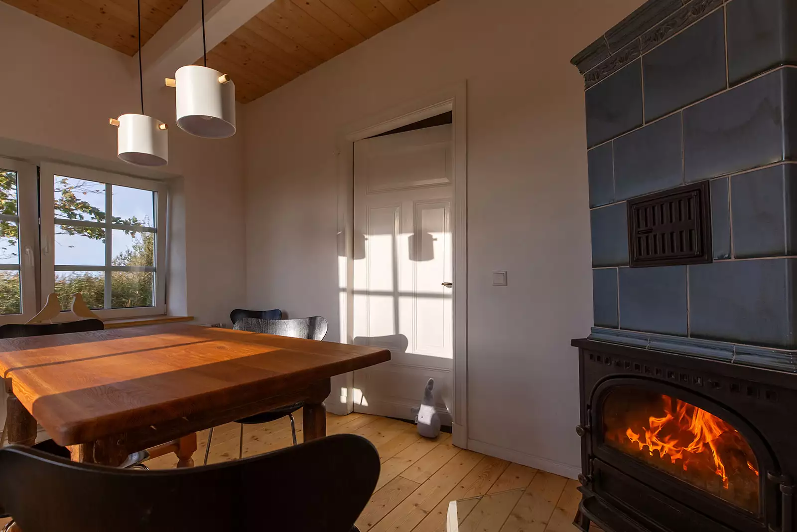Esszimmer im Deichschlösschen mit brennendem Kachelofen und Esstisch