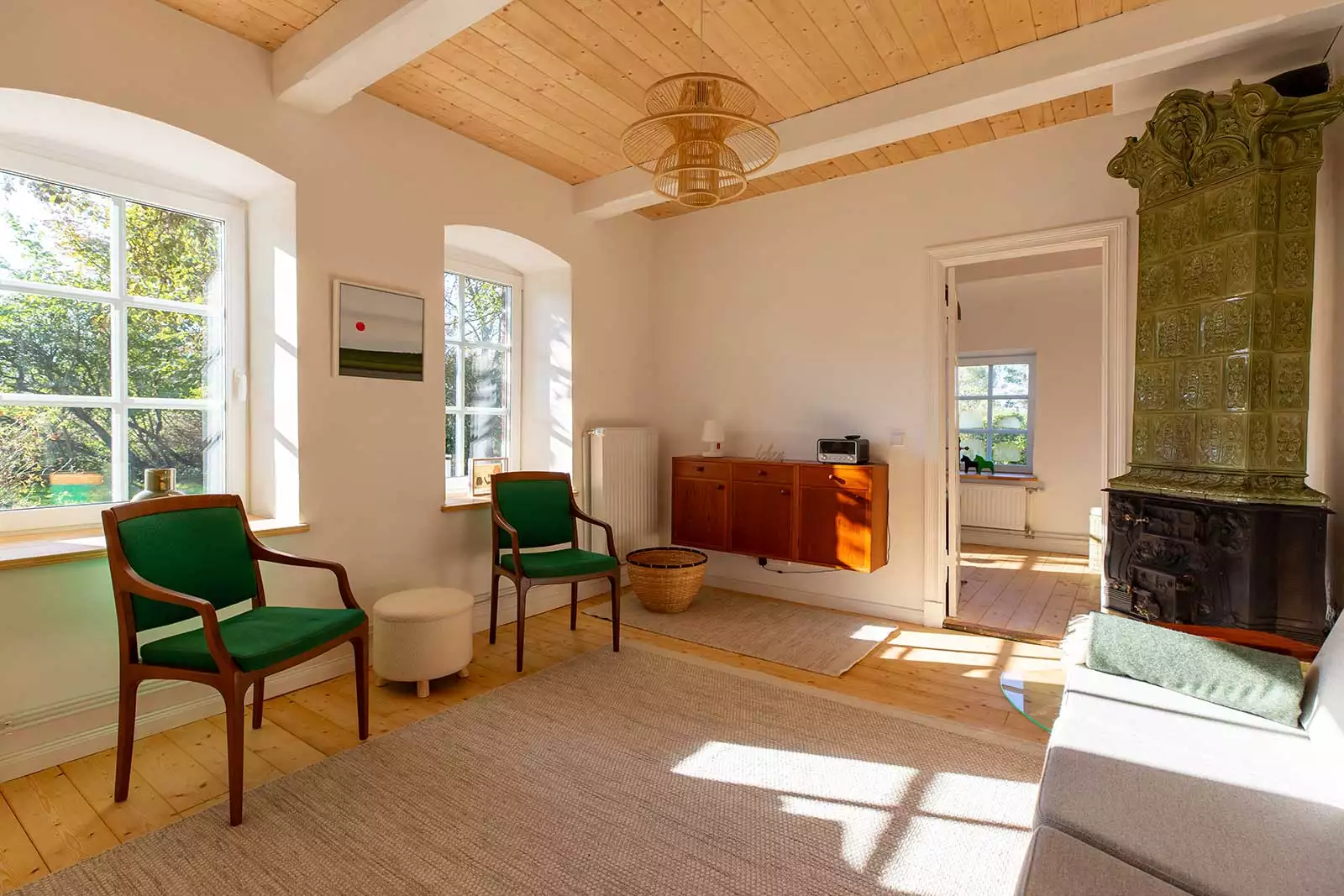 Wohnzimmer im Ferienhaus Deichschlösschen mit Kachelofen, Couch und Blick ins Lesezimmer