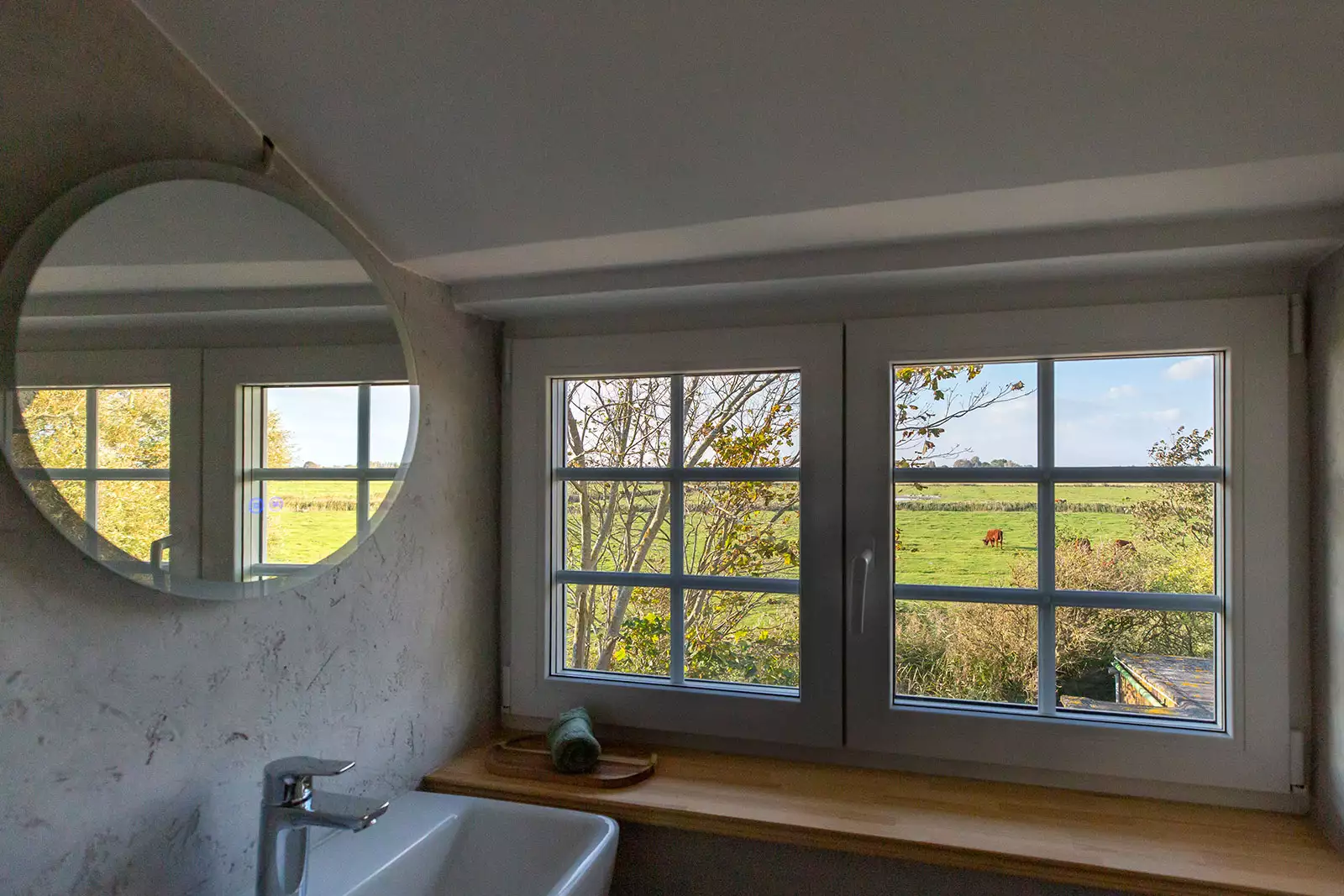 Badezimmerfenster im Deichschlösschen mit Blick auf die Fenne und Kühe