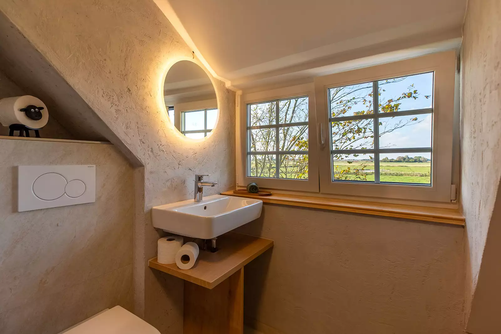 Badezimmer im Deichschlösschen mit WC, Waschbecken und Blick auf die Weide