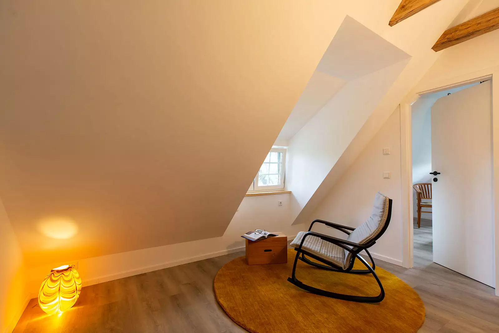 Dachgeschossgalerie im Deichschlösschen mit Schaukelstuhl, Teppich und Zeitung